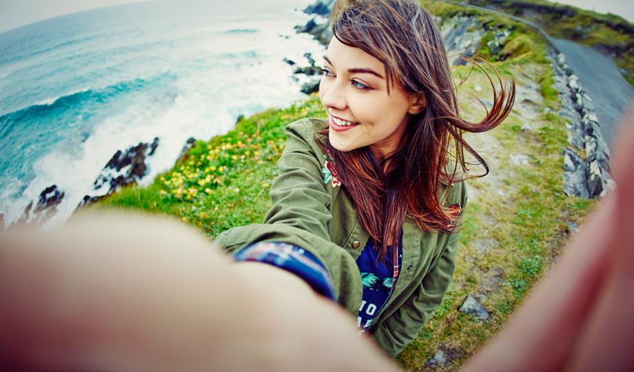A young woman takes a selfie on the Irish coast